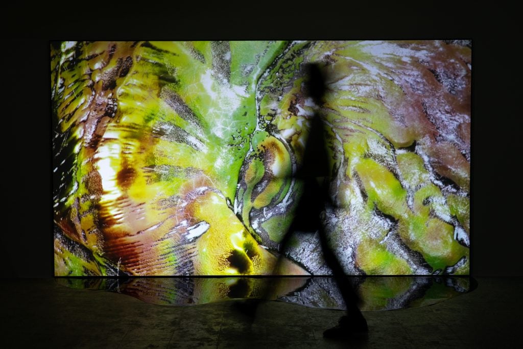 A person walking in front of a gigantic screen