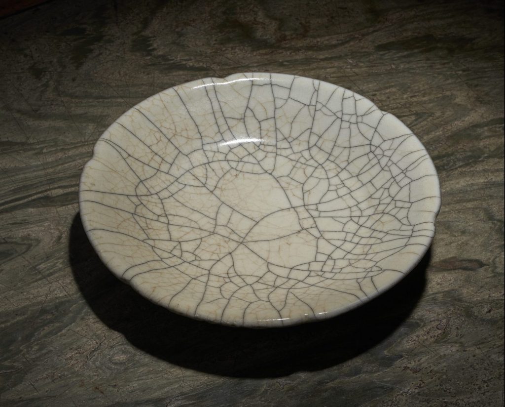 A ge foliate dish from southern Song to Yuan dynasty (1127-1368). The dish is shallow with a greyish cracked glaze and slightly scalloped edge