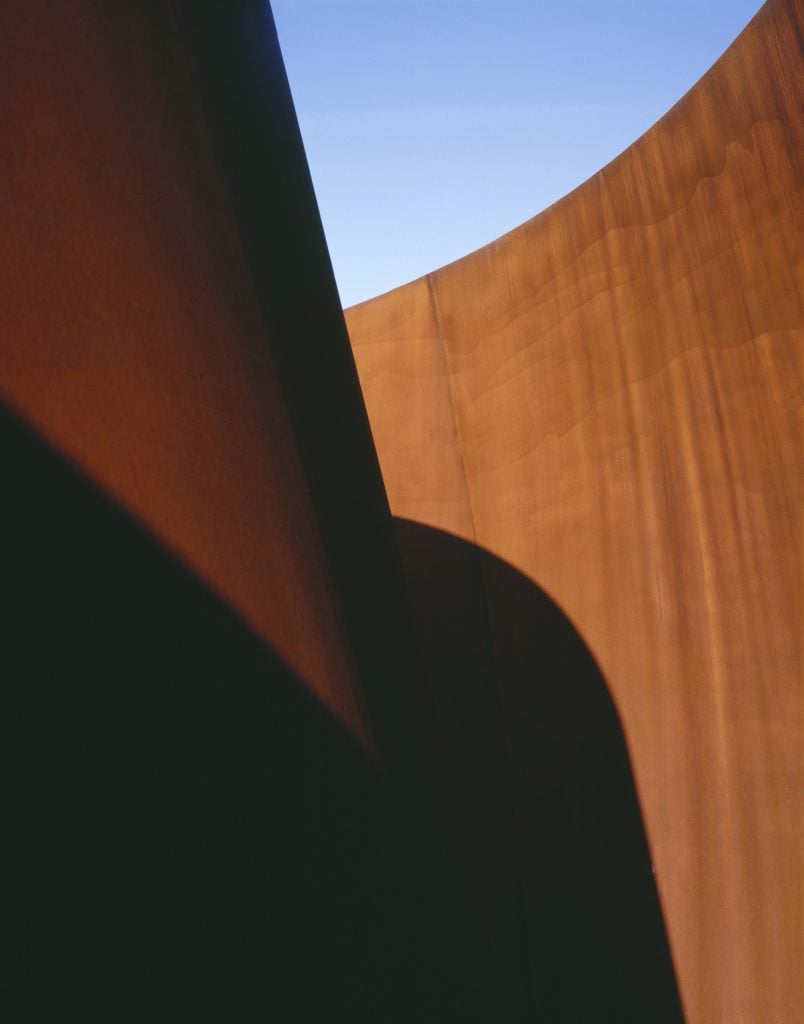 Detail of the an iron sculpture by Richard Serra, featuring swirls of cor-ten
