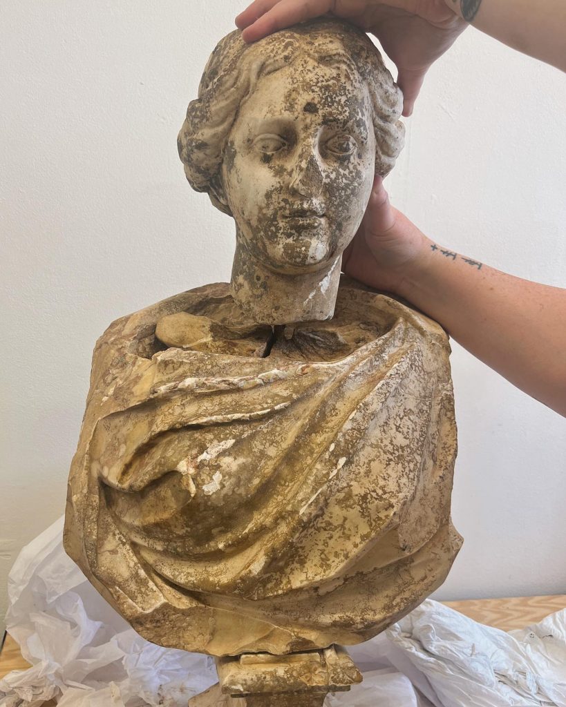 A pair of arms fitting the head of a sculpture to its body.