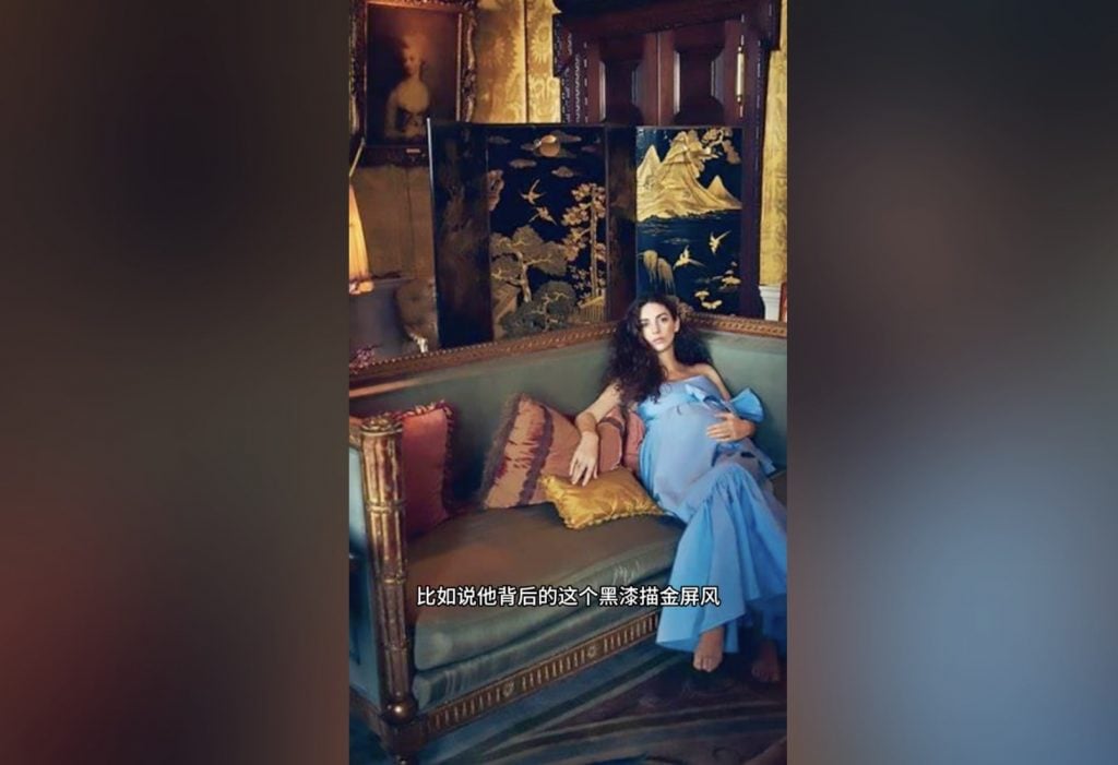 A woman in a blue dress reclining on a luxurious couch, with a Chinese screen behind her.
