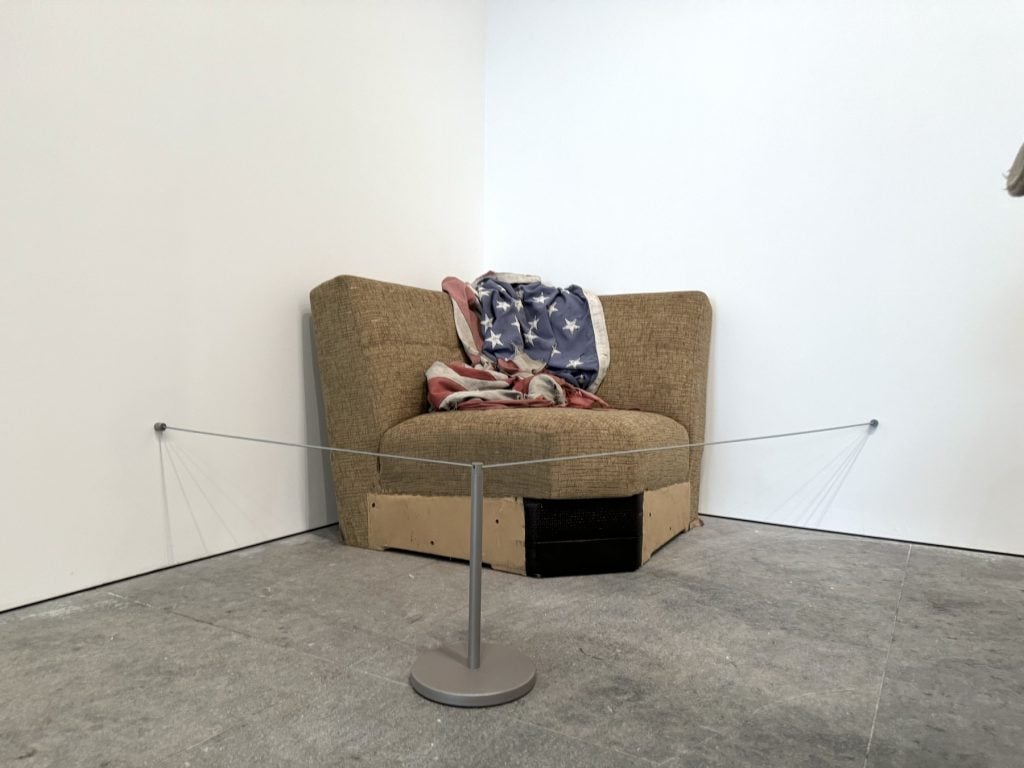 A dirty section of a couch with an American flag on it in an art gallery