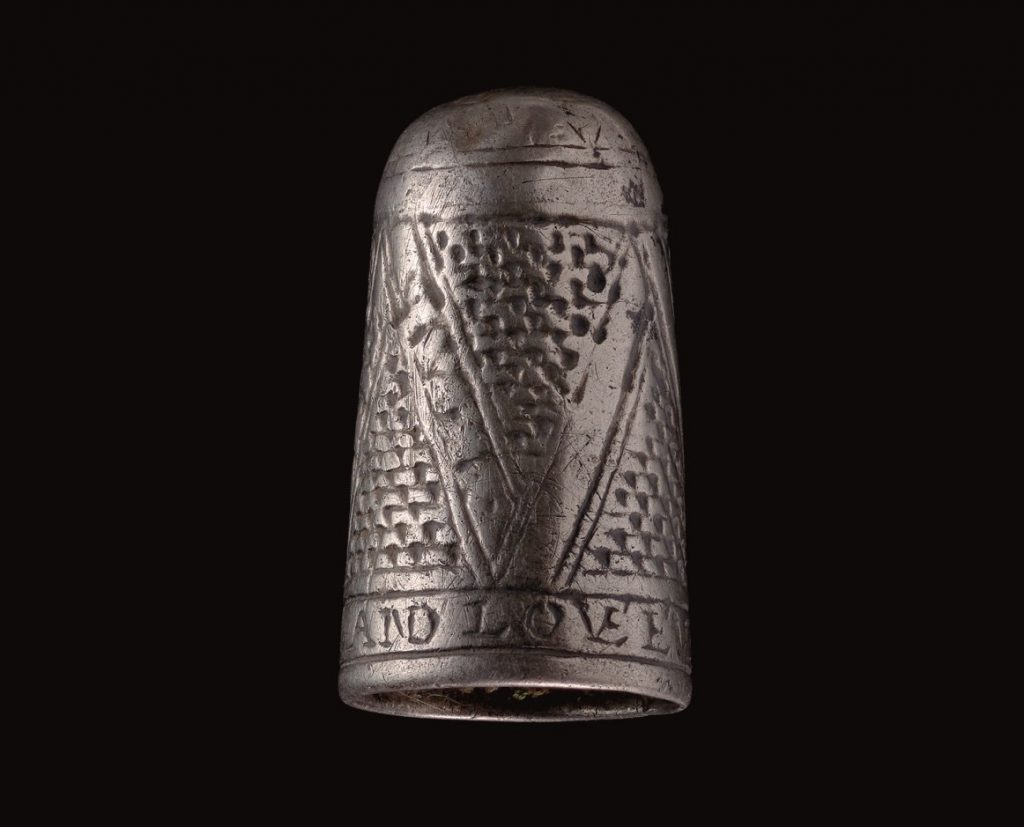Silver thimble on black background.
