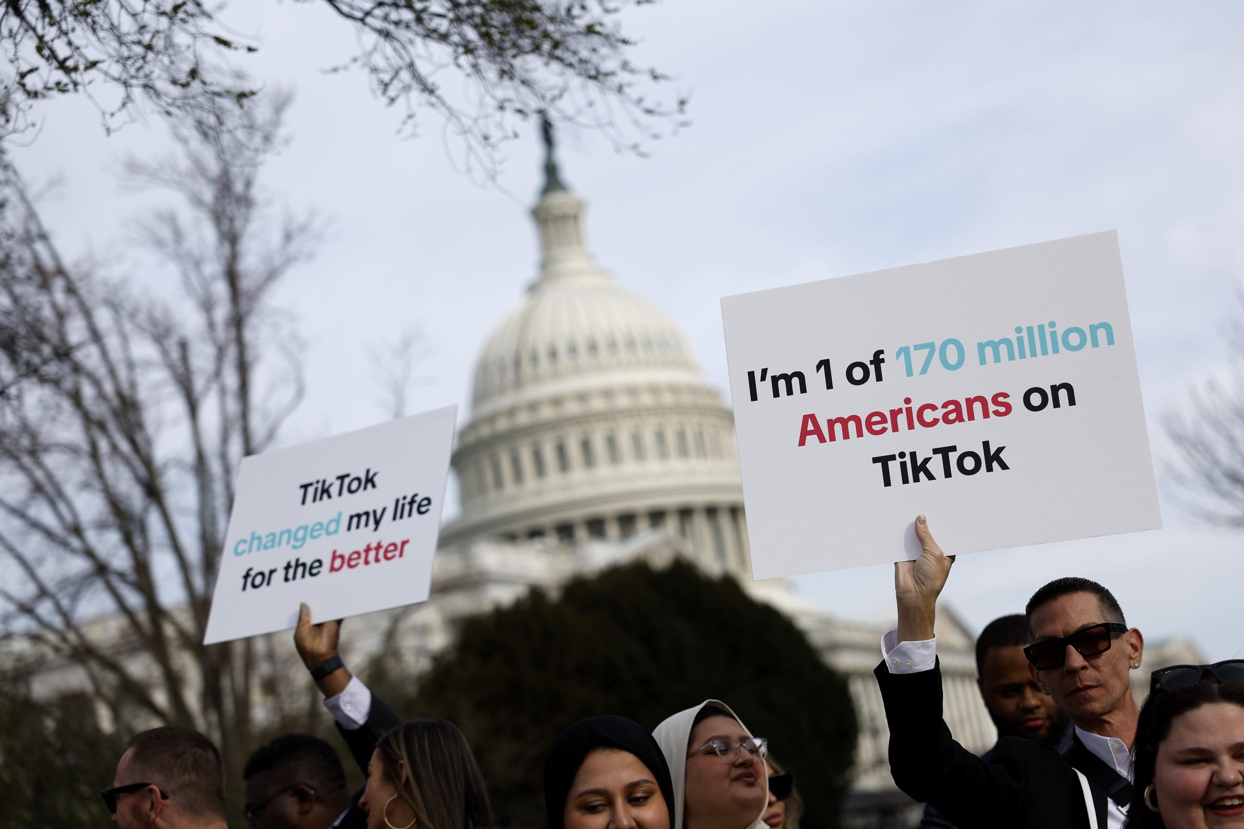 The image shows a group of people standing in front of the US Capitol building holding signs. One of the signs reads "I'm 1 of 170 million TikTok Americans on changed my life for the better TikTok."