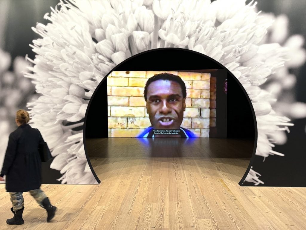 A round entrance to a gallery surrounded by the image of a flower with an image of a film playing within