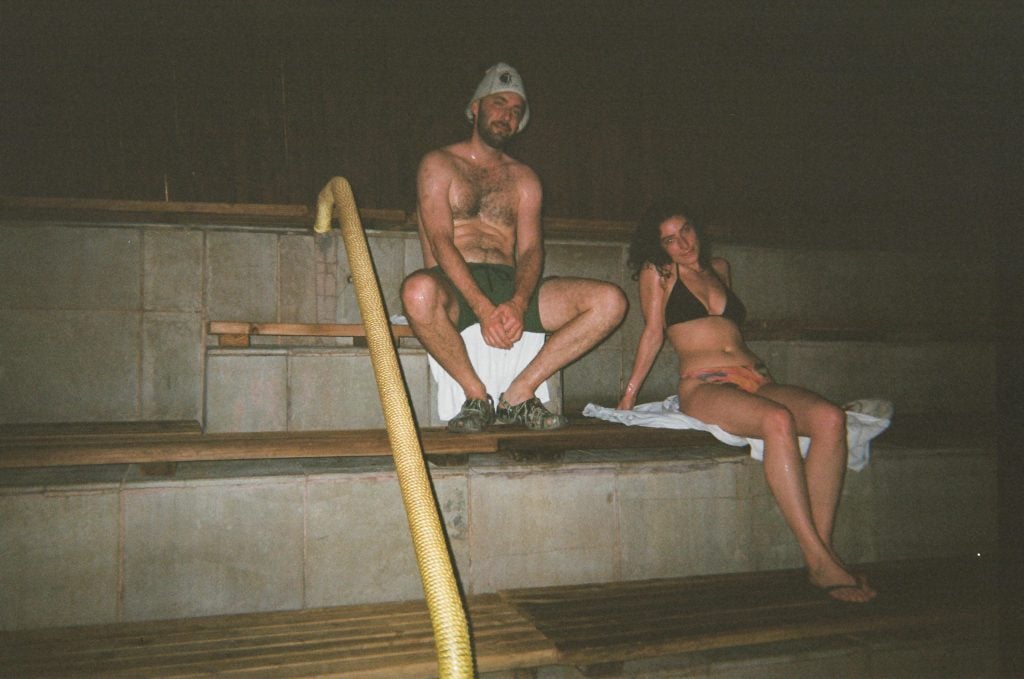 Two people wearing bathing suits sit on the steps of a spa.