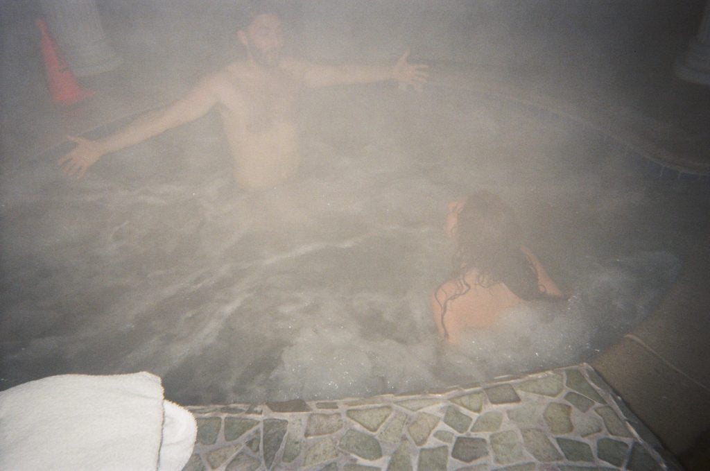 a hazy picture of two people goofing around in a hot tub.