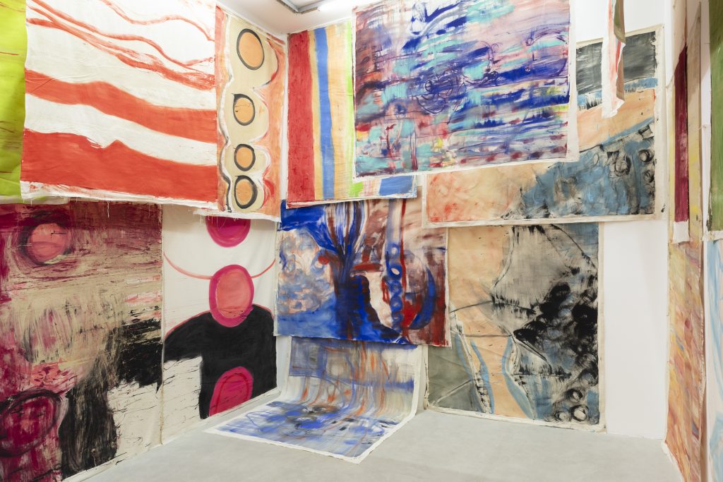 An instalation view of a room overlaid with various large-scale images.