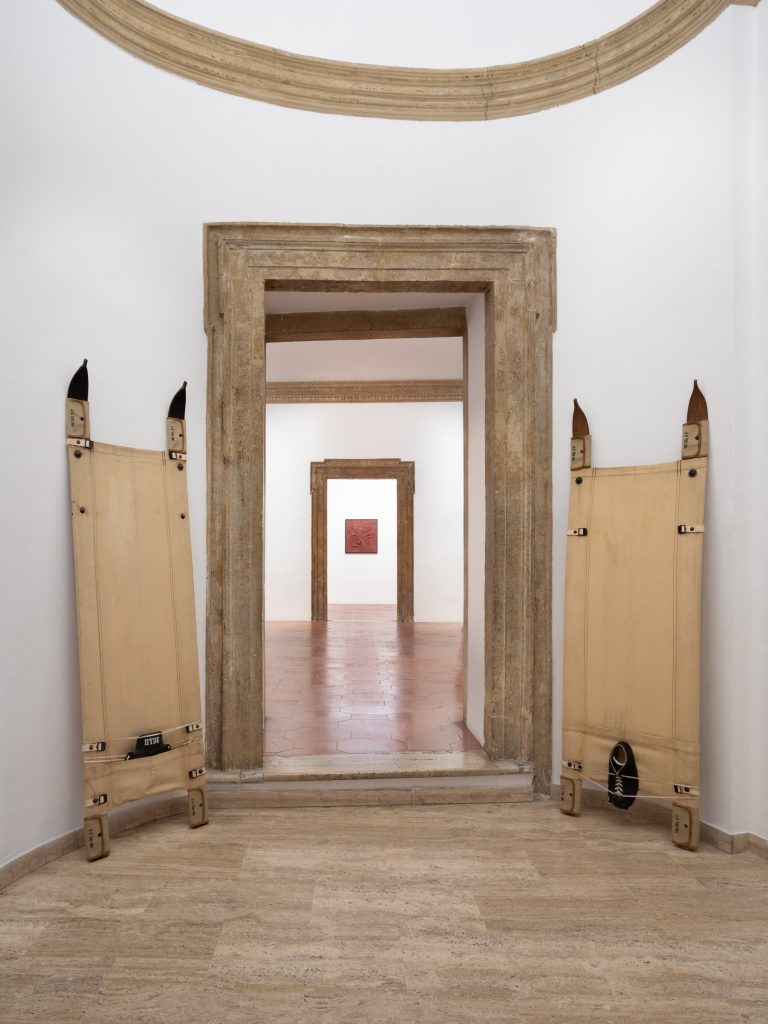 Installation view of work by salvatore scarpitta with two upright sleds on either side of a marble doorframe.