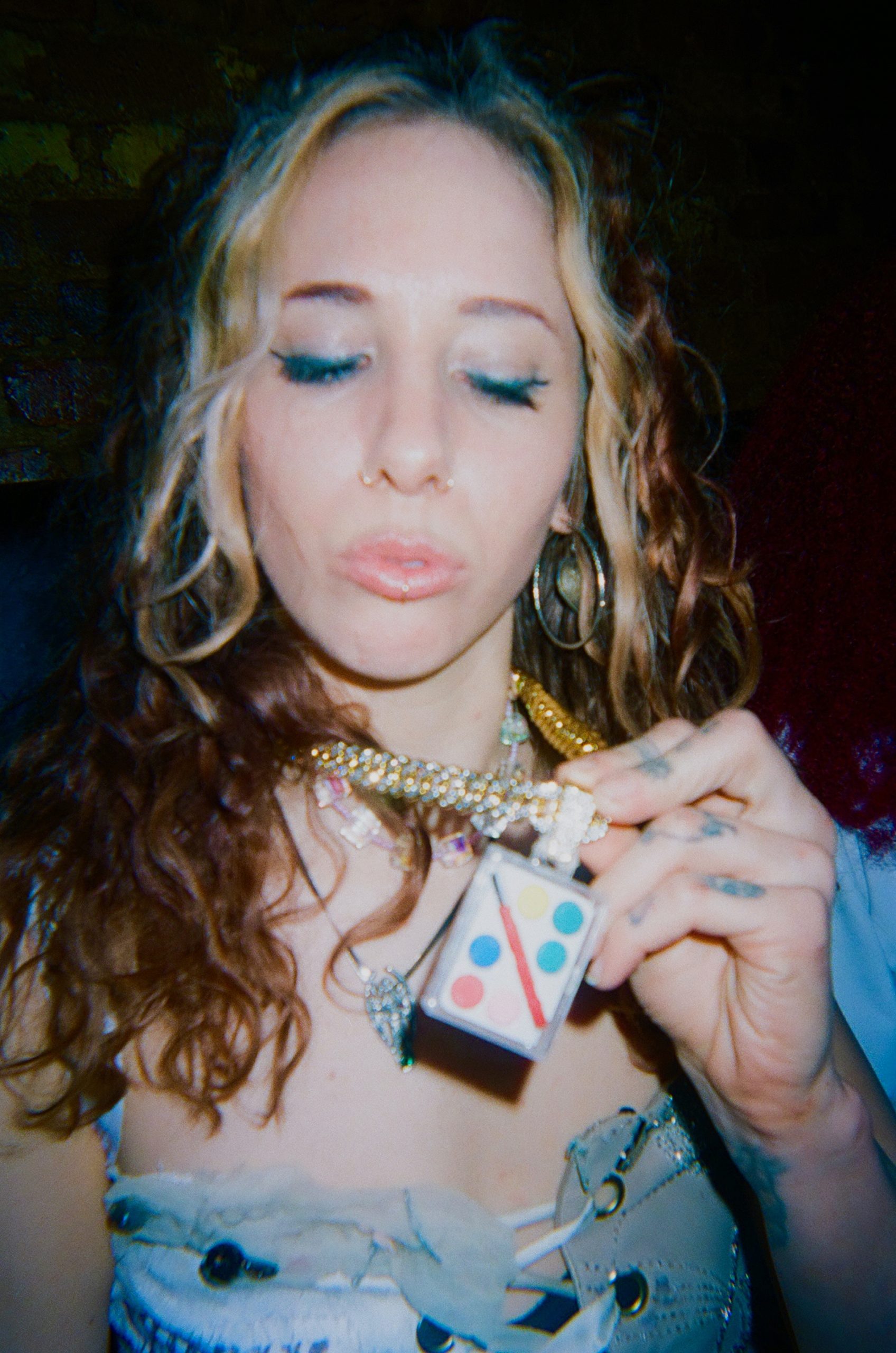 An artist poses with a necklace made of a painter's easel.