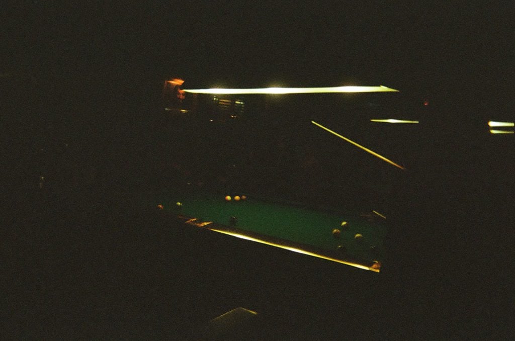 A lowly-lit pool table. 