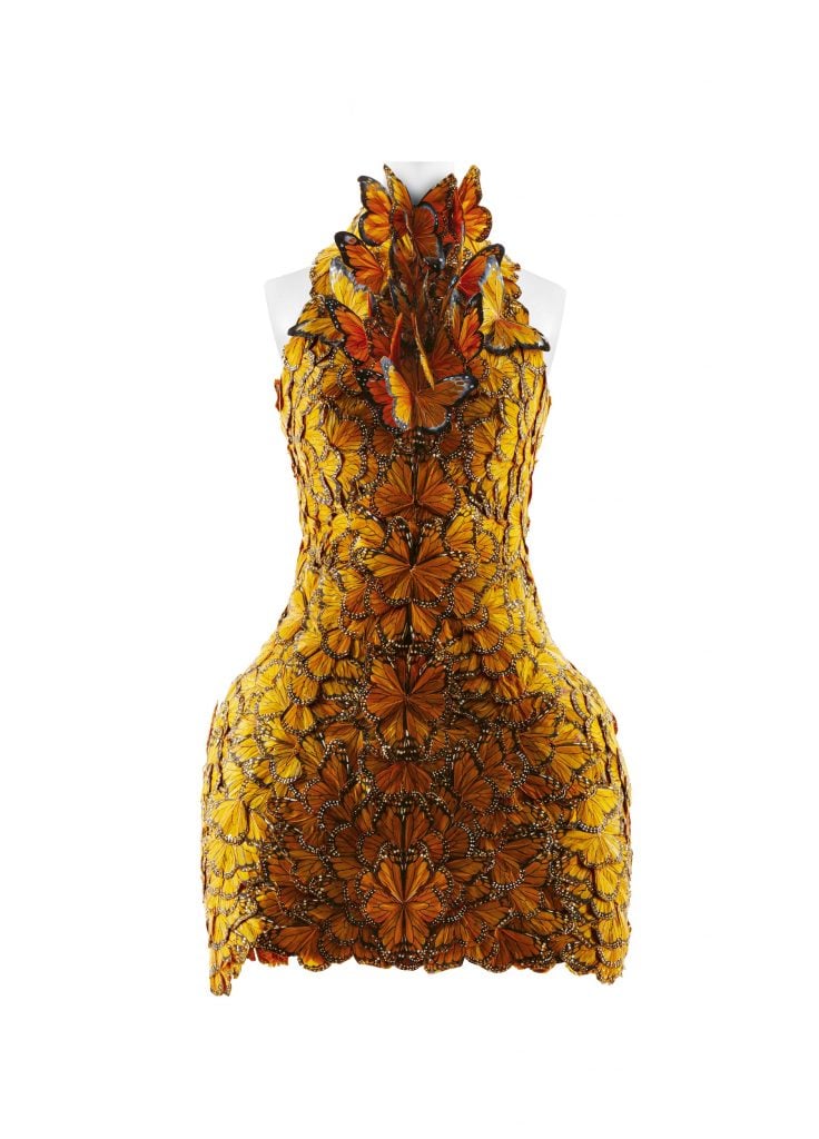 A short dress designed by Sarah Burton covered entirely in orange butterfly wings, with a group of butterflies at the neck