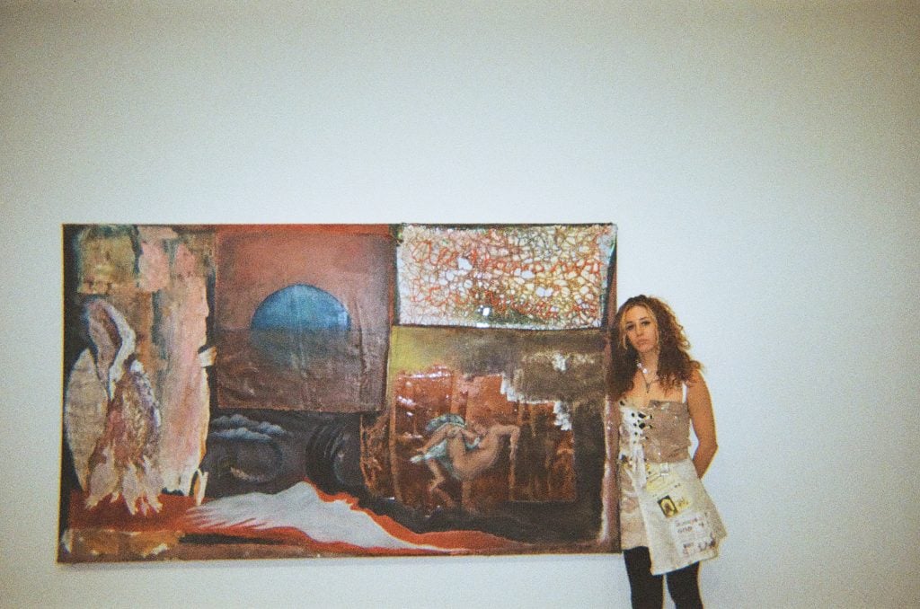 An artist standing in front of a painting she made. 