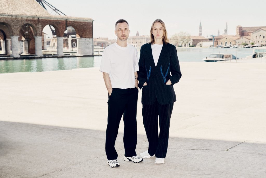 a young man and woman standing near the arsenale in venice