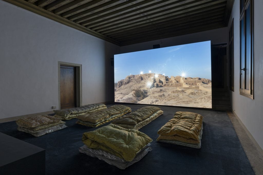 A room installed with cushions, with a large screen showing a desert scene