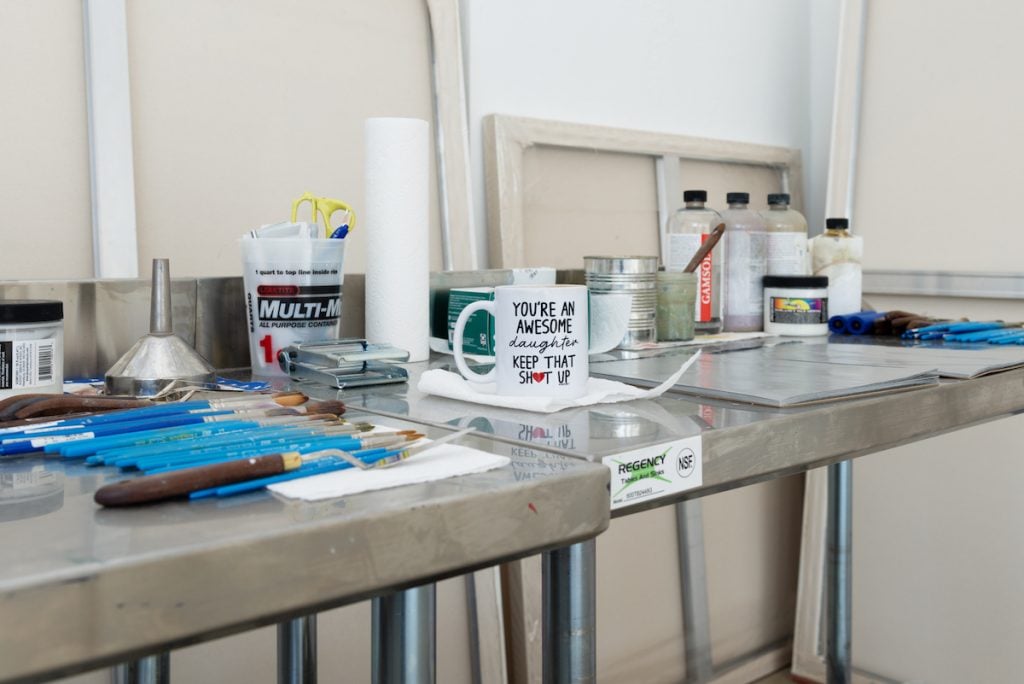 view of a studio table including brushes and a coffee mug