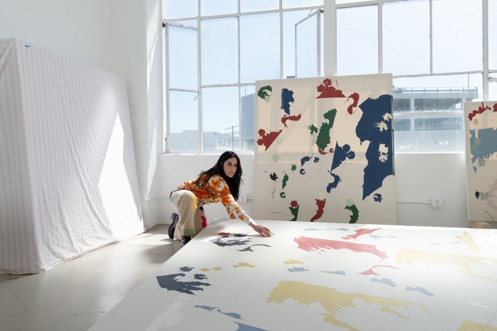 image of a woman in her studio painting on a canvas on the floor