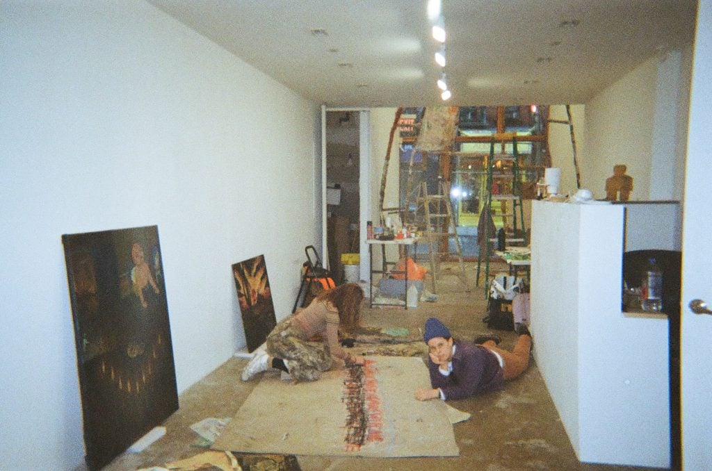 A painter puts some finishing touches on her artwork on the floor of an art gallery. 