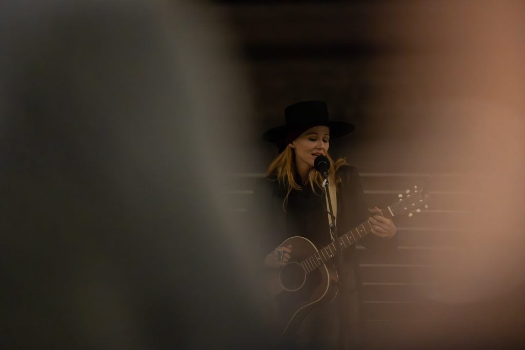 an atmospheric photo of a woman playing guitar and singing. the setting is dark and hazy