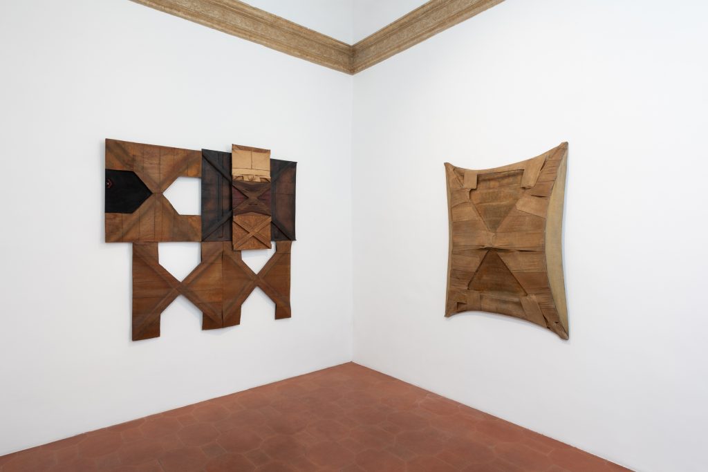 Corner of a gallery room with one flat work on either wall by salvatore scarpitta.