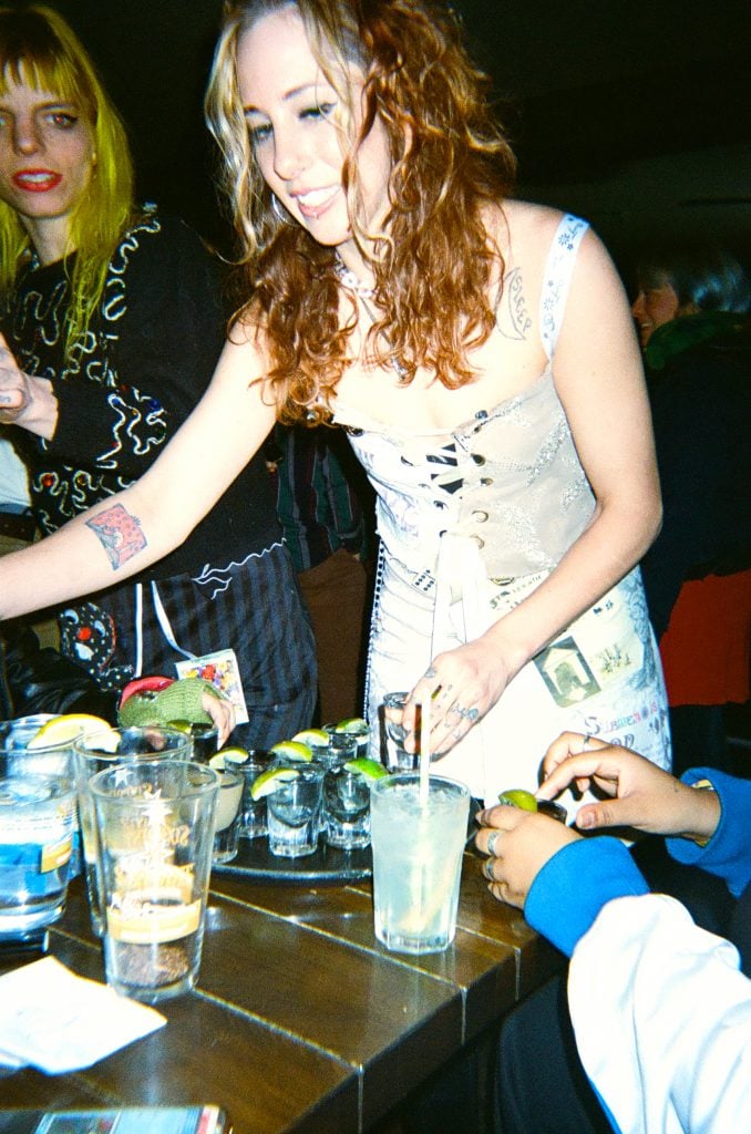 A woman pours shots for friends at a bar. 