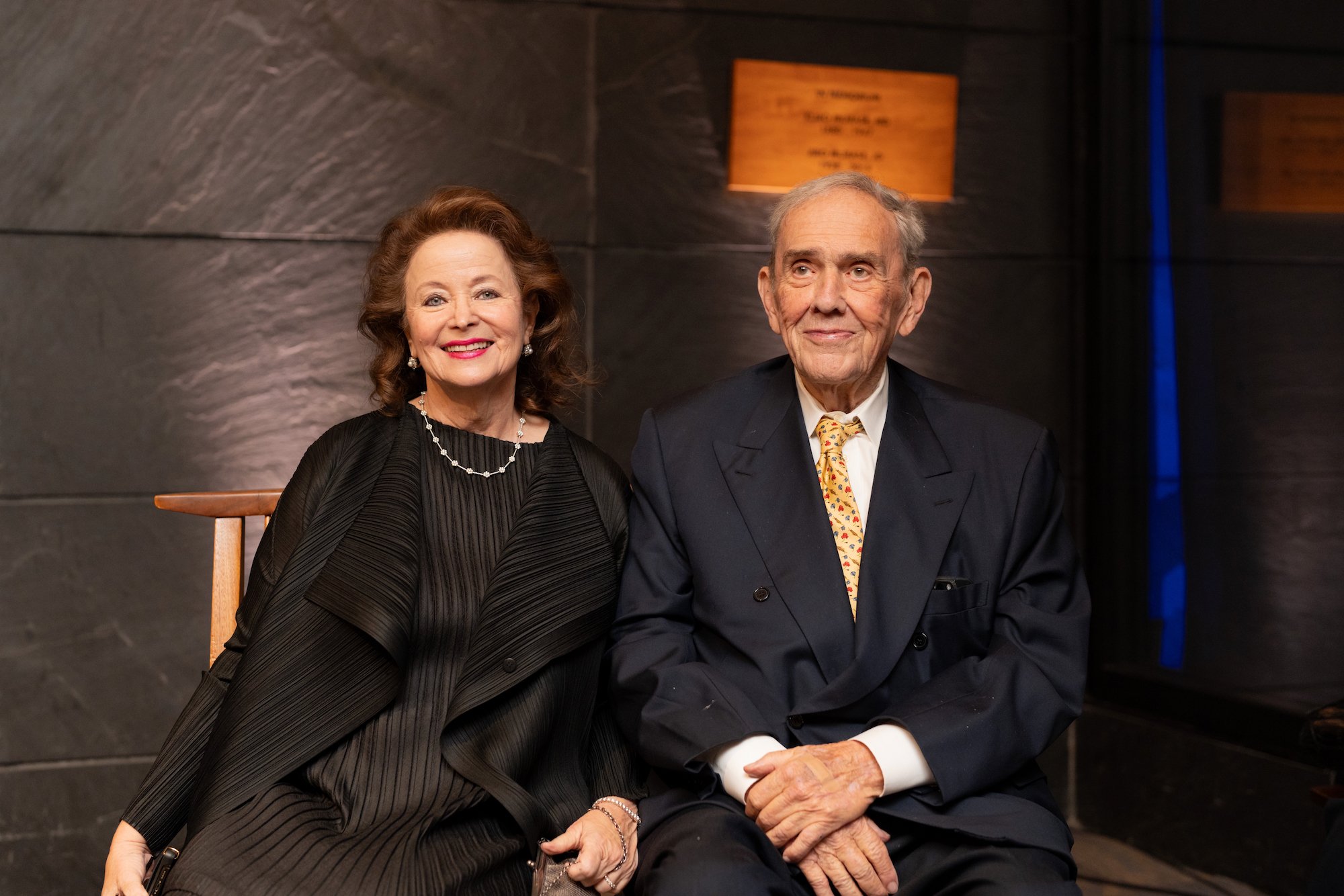 picture of a caucasian lady dressed in black with a caucasian man on the right, in suit