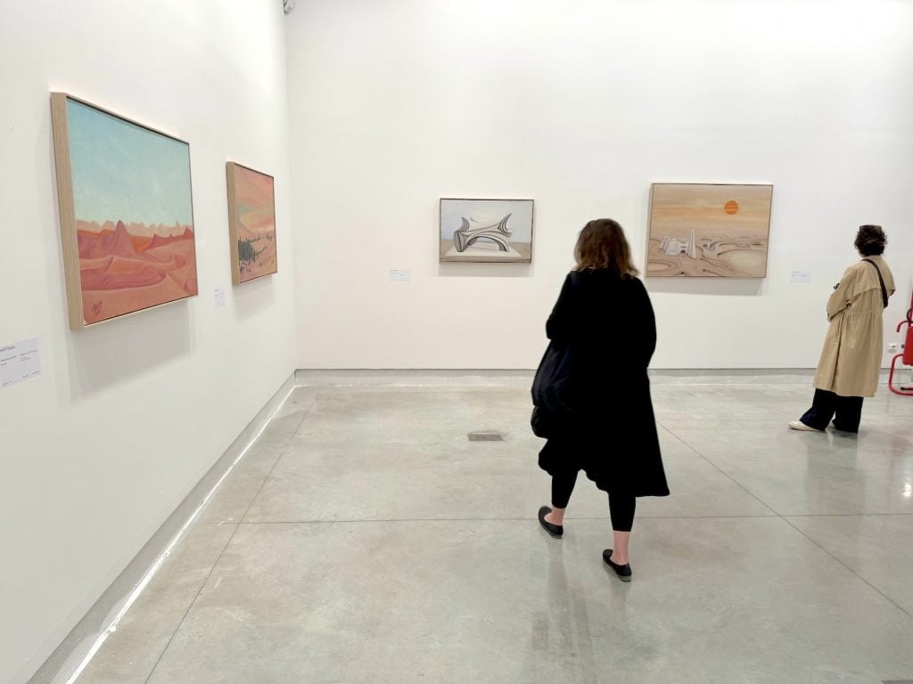Visitors view paintings of mysterious desert scenes