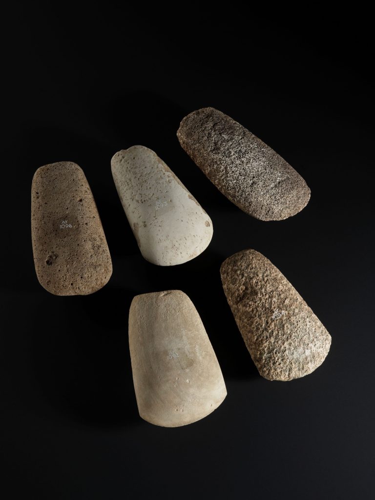 group of five Neolithic ax heads on a black background