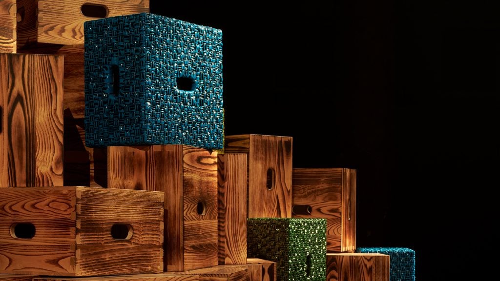 a close up of a colorful leather wrapped designer crate designed by Bottega Veneta sitting atop wooden ones 