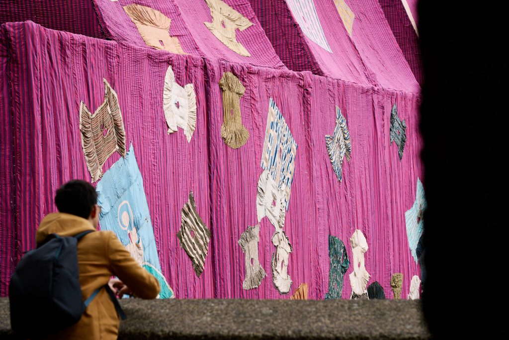 a large tent like draping bright pink tapestry installed outside