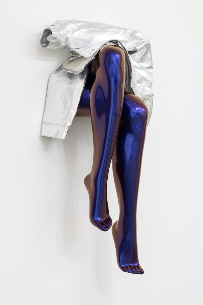 A wall-hung fibreglass sculpture showing a jacket draped over legs colored in blue