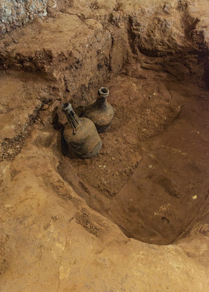 Two glass bottles half exposed from the earth.