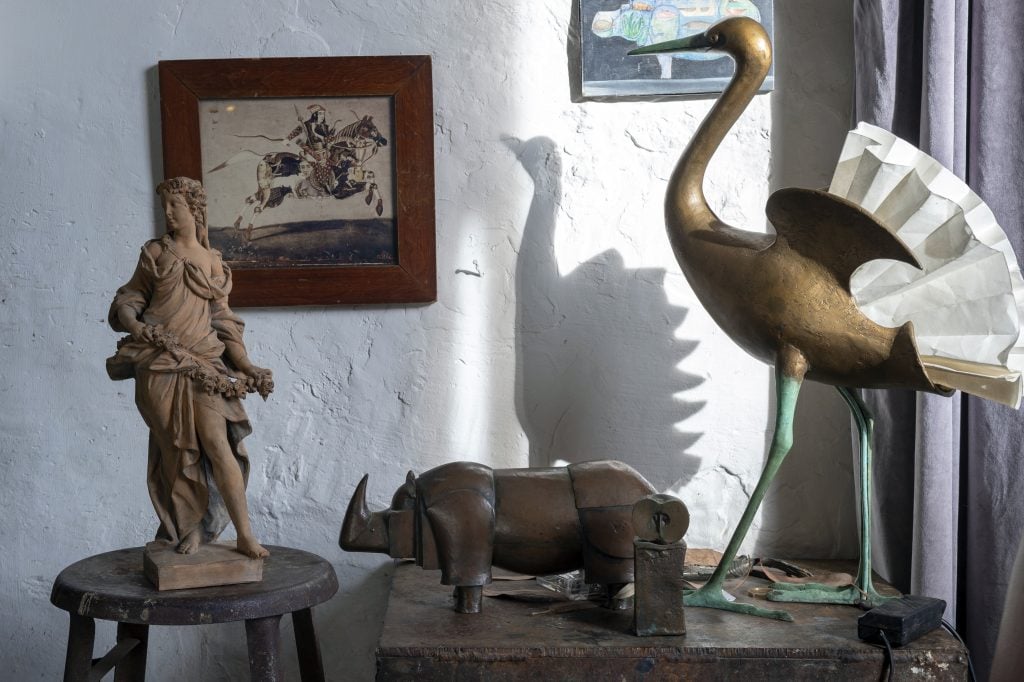shadows fall on small sculptures of a woman, a rhino, and a bird in the Les Lalanne studio 
