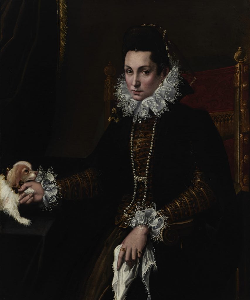 An image of a dark Renaissance portrait depicting a mourning, sullen woman in all black formal wear, holding a handkerchief in one hand and the paw of a toy spaniel in the other