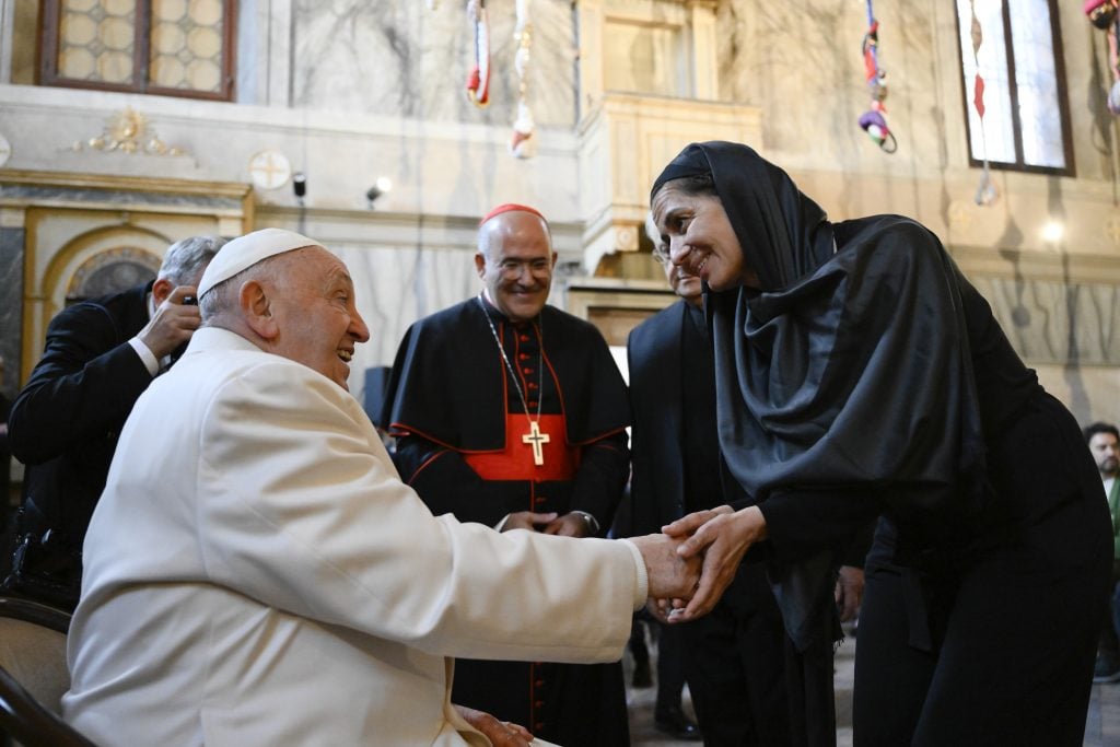 the pope shakes hands with a woman in black in a church