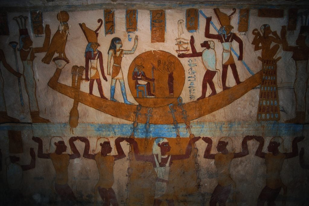 a mural of ancient Egyptians on a boat with a round sun on the boat