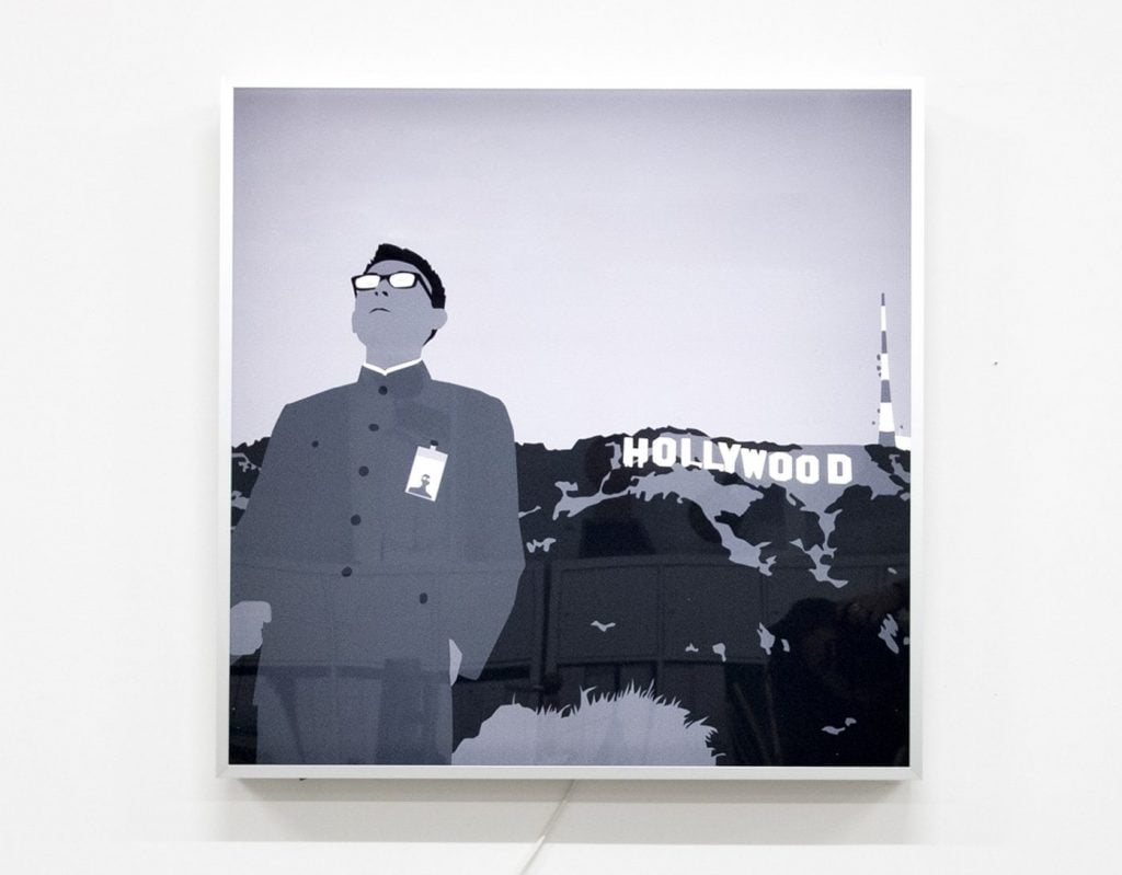 An East Asian man standing against the backdrop of 'Hollywood'