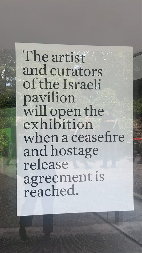 a piece of paper taped to a glass window indicating that the israel pavilion at the venice biennale will remain closed