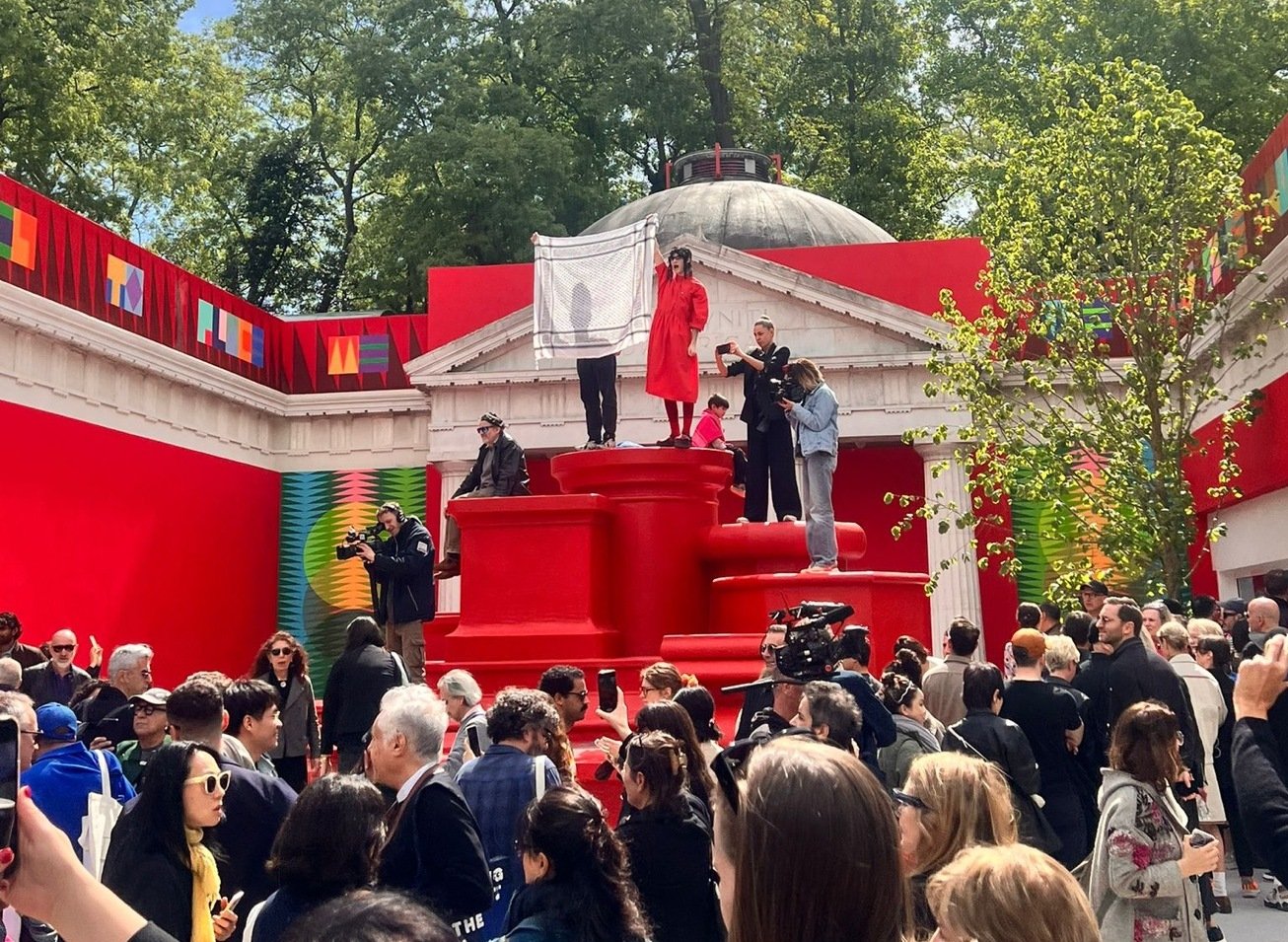 protestors stand outside of a building identified as the US pavilion at the venice biennale