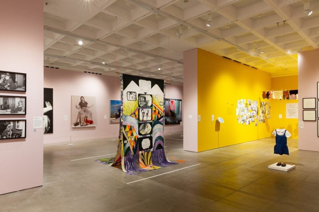 a large, brightly lit, complex gallery space hung with art