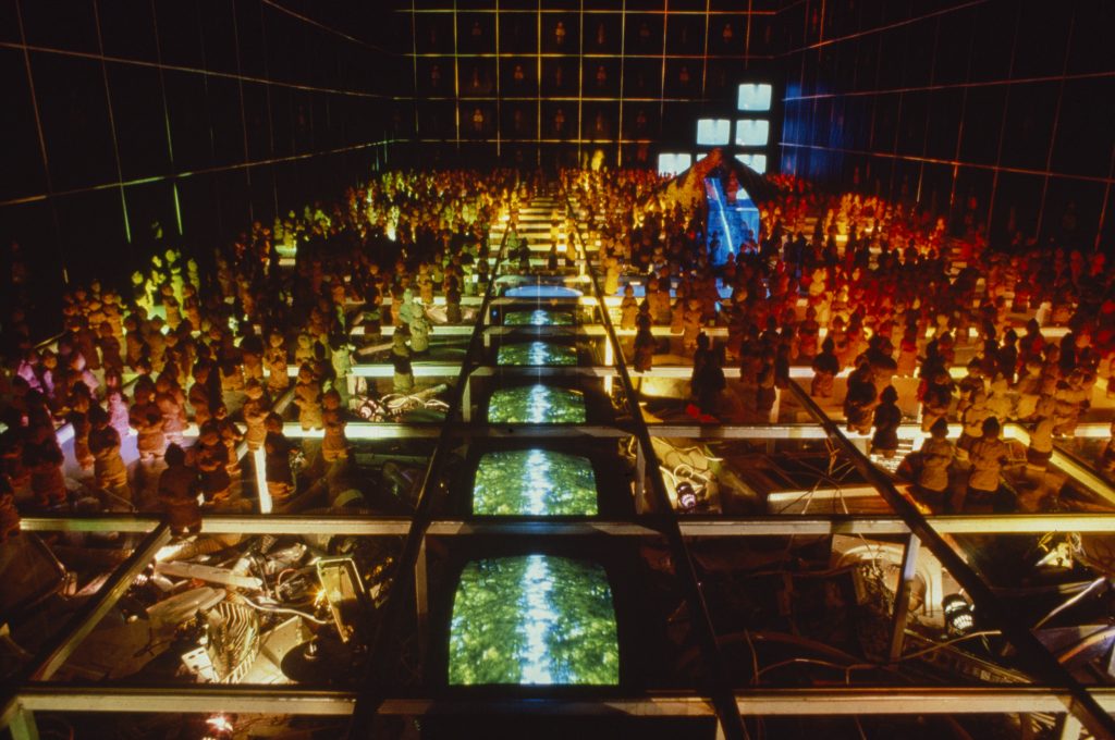 This image shows a colourfully lit installation mounted above water, with what appears to be chess pieces standing on top of the surface.