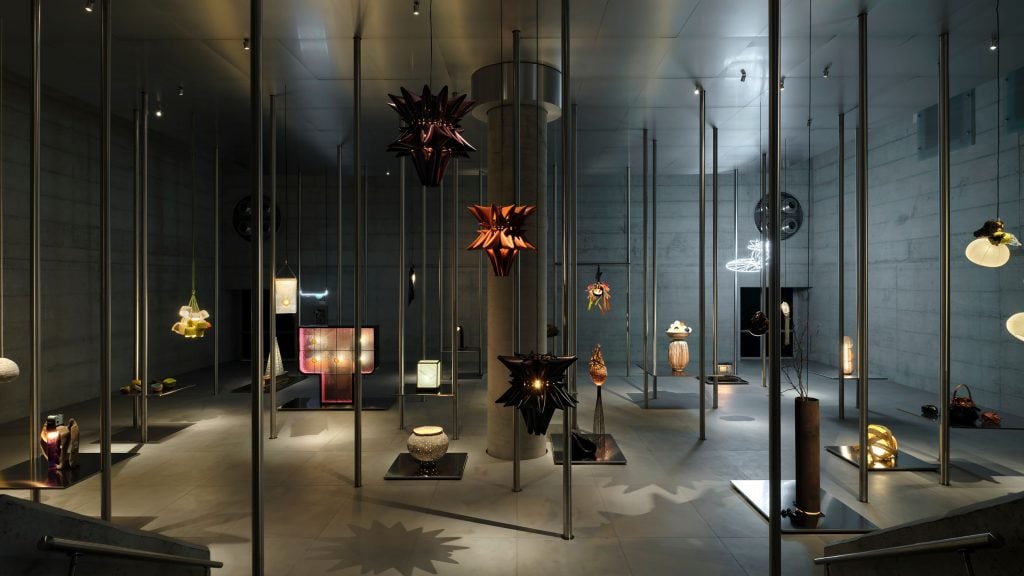 an assortment of artistic designer lamps hang in an industrial basement