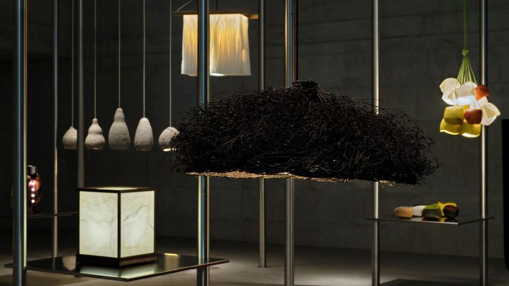 many intricate artistic sculptural lamps are set against a dark background 