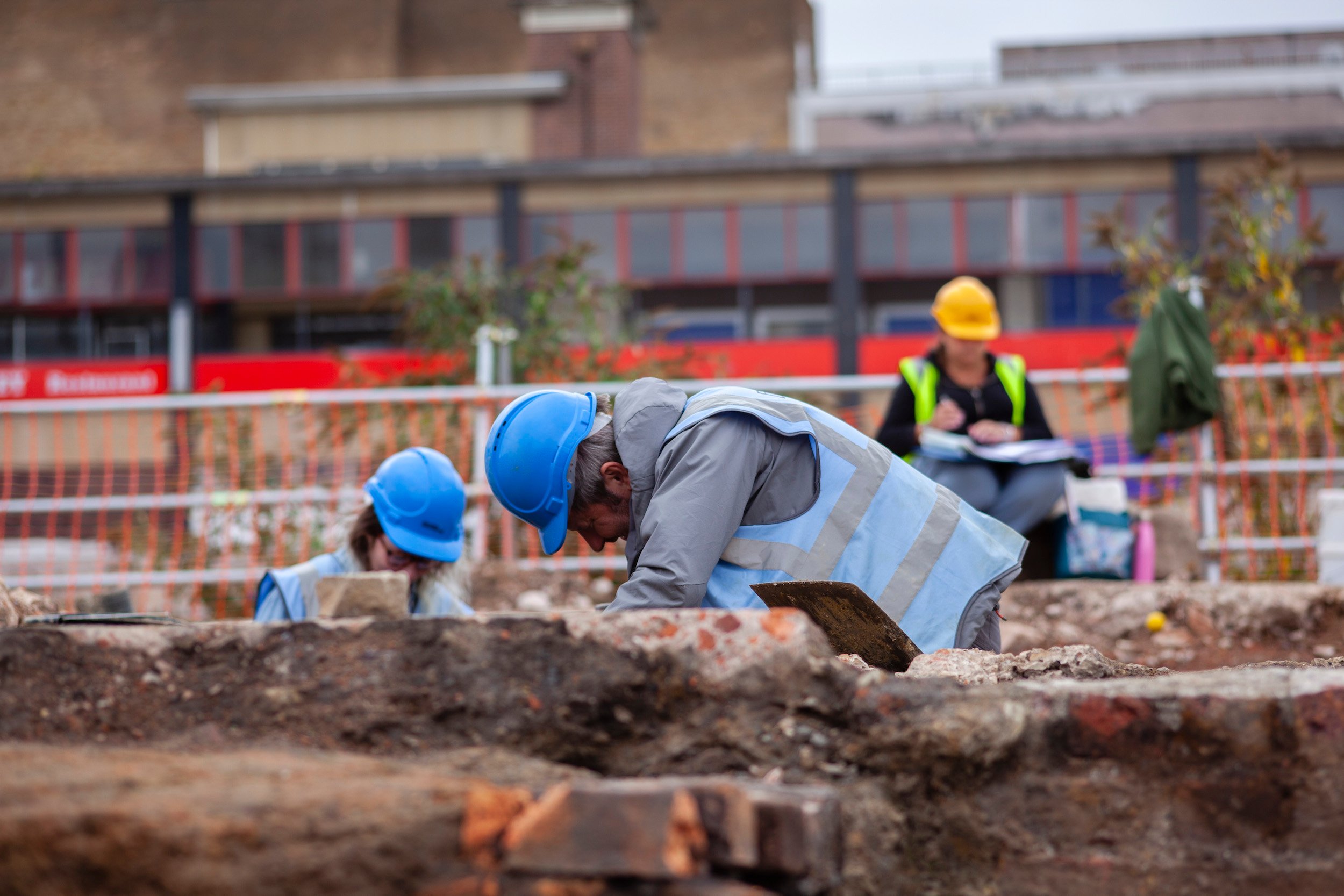 People in hard hats and high vis assisting with a dig.