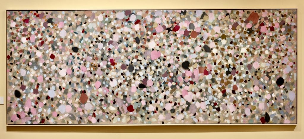 a long abstract painting with dots of black, pink, red, and white