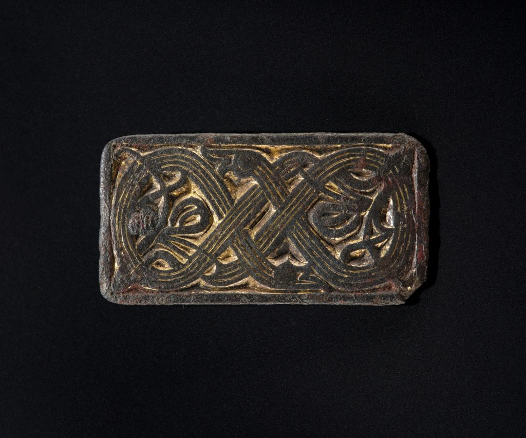 a bronze buckle with a looping pattern.