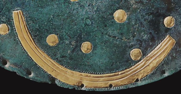 a gold curve on a blue-green background with many small incisions off of it. 
