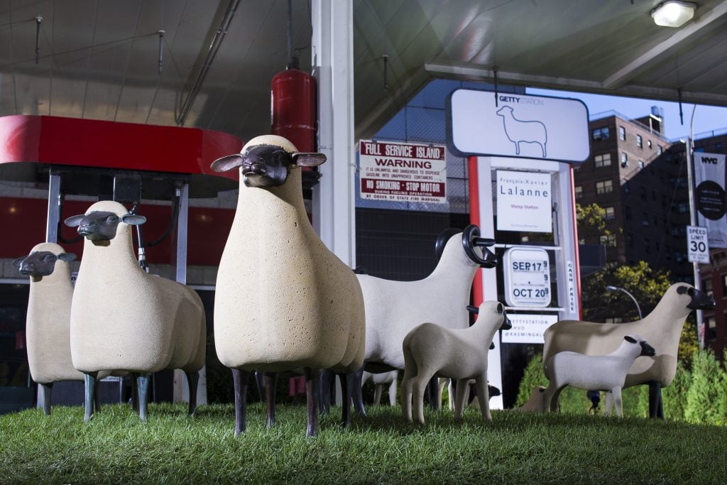 Les Lalanne sculptures of sheep are atop fake grass outside of a Manhattan gas station. 