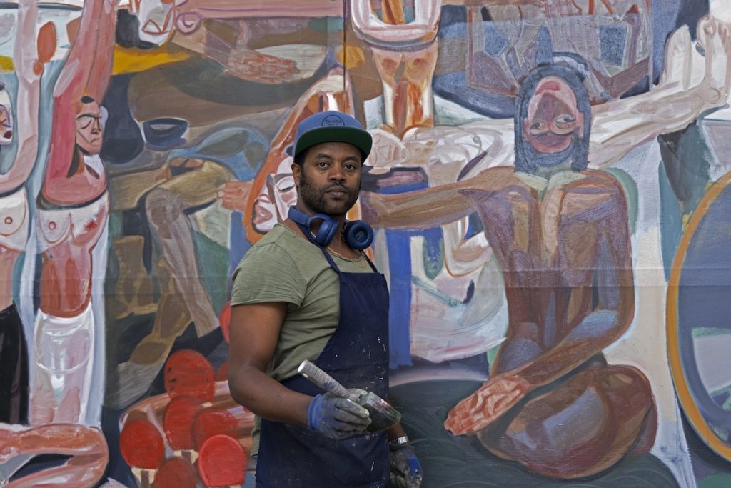 artist Tesfaye Urgessa, who is representing Ethiopia at the Venice Biennale, standing in front of a large figurative painting he made 