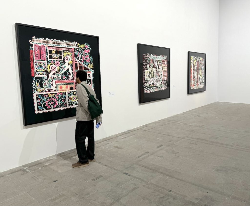 A person looks at carious large papercut works in an art gallery